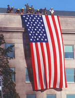 Firefighters and military personnel lower a U.S. flag from the roof of the Pentagon the day after it was attacked. Department of Defense photo by R.D. Ward.