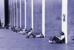 A row of students relax against the concrete posts of Kane Hall on a sunny day in Red Square in this 1980s shot. File photo.