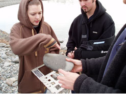 Students measure cobblestones on the beach.