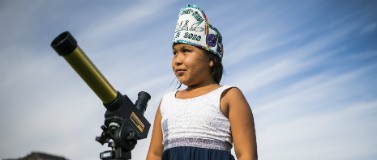 A student looks through a telescope.