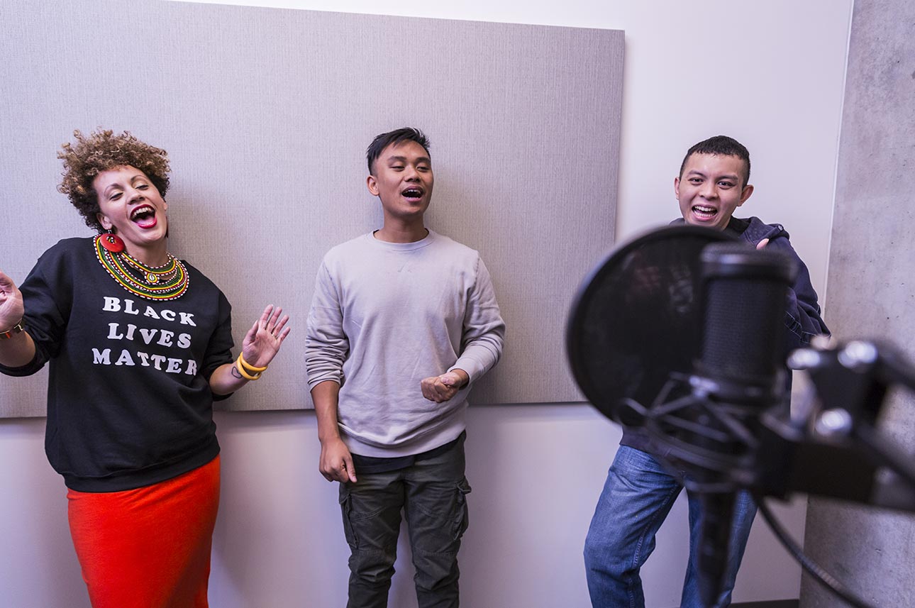 Assistant Director and lead producer Aina Braxton, ’12, composer Bryce Villanueva, ’16, and test-team member JC Ignacio share a laugh in the recording room