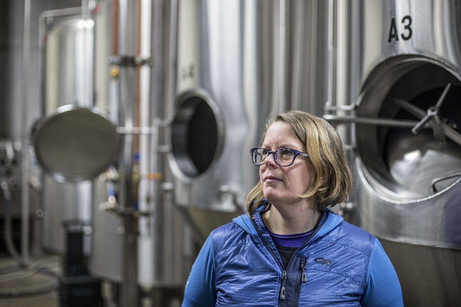 Lisa Ulrich standing by brewing vats