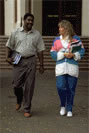 A man and woman talk as they exit the building, books in hand
