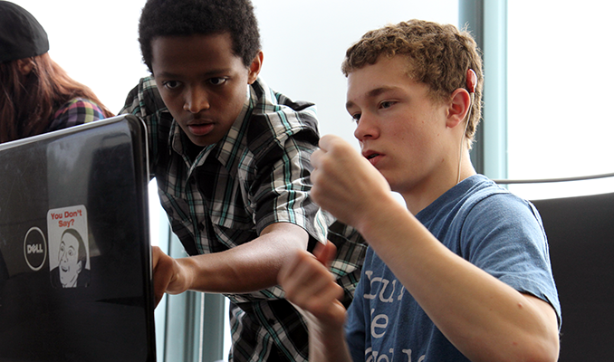 A computing student uses sign language to communicate to with another student