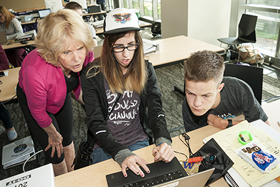 An instructor helps students with online research.