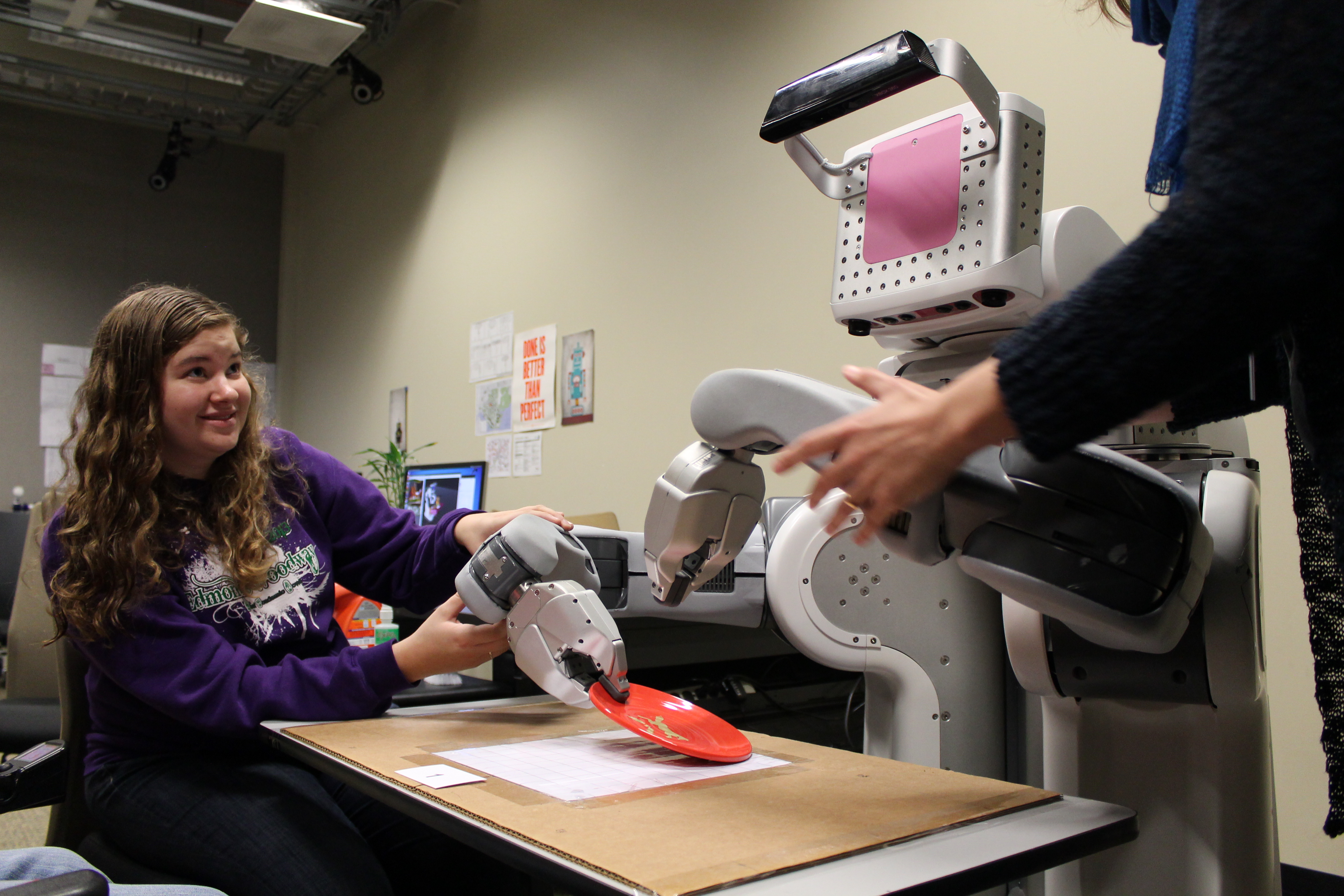 A student and instructor work with a robot.