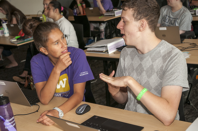 Two students signing while in a computer lab. Two students signing while in a computer lab.