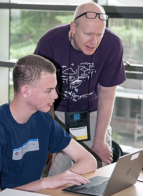 An educator helps a student on a computer.