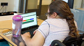 A student in a wheelchair uses a laptop.