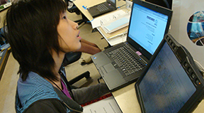 A woman uses a computer as well as assistive technology.