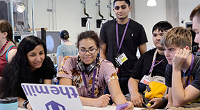 An instructor works with four students with disabilities around a computer.