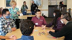 Sheryl stands next to a table of DO-IT participants, sharing in a discussion.