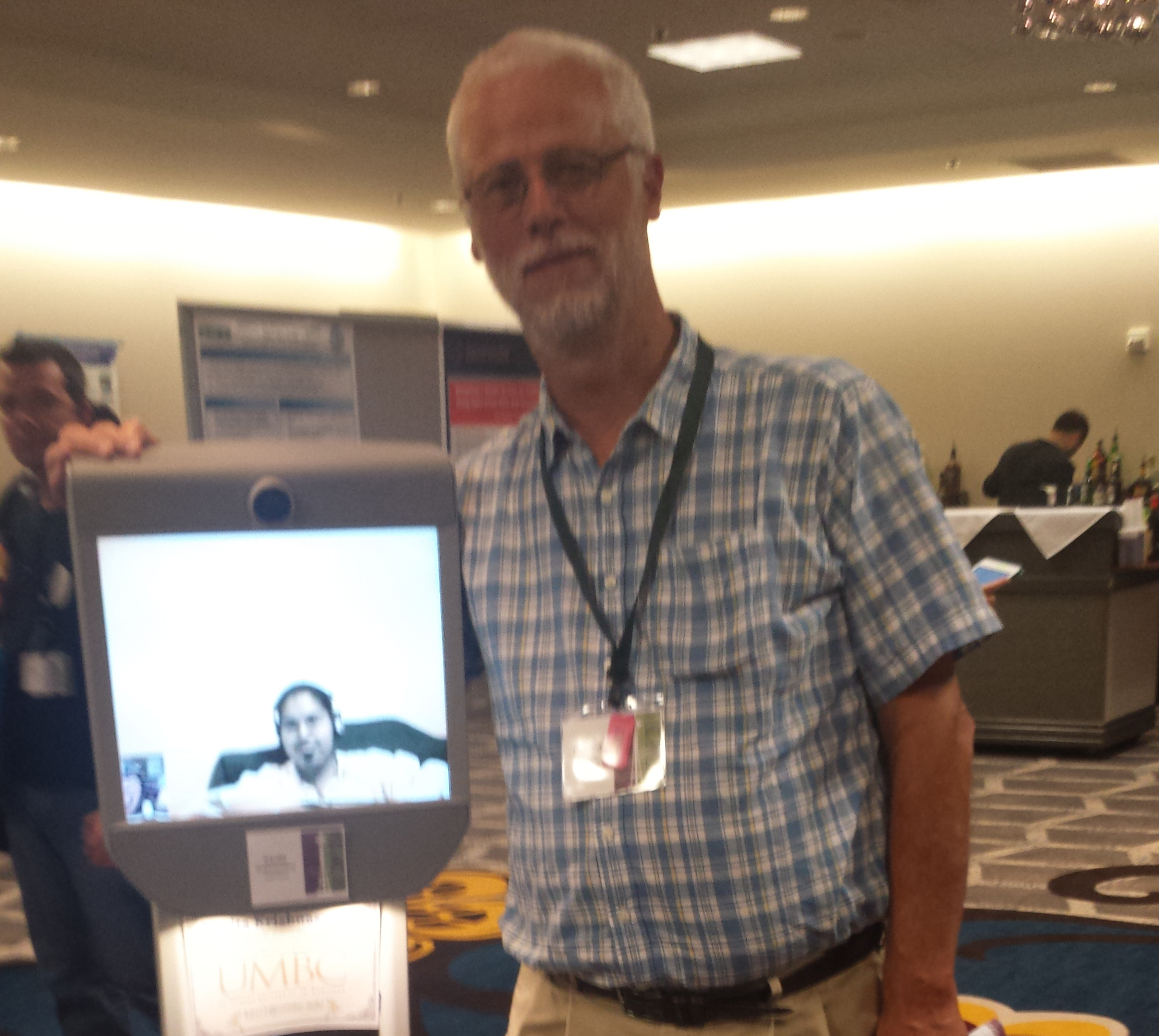 Richard Ladner standing next to Kavita (on screen) in her Beam Robot.