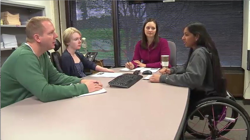 
Still image from video: A diverse group of individuals meets around a large table