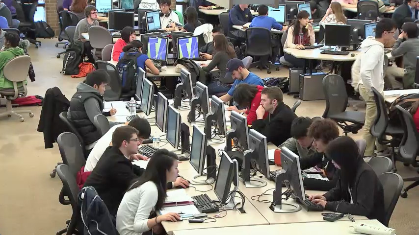 
Still image from video: Students working in a large open computer lab