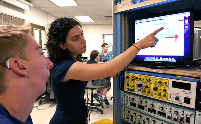 A student with a hearing impairment and an educator look at data on a monitor A student with a hearing impairment and an educator look at data on a monitor