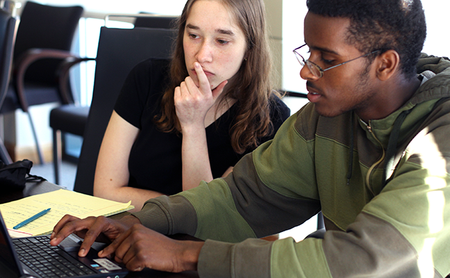 Two students collaborate on a computing project Two students collaborate on a computing project