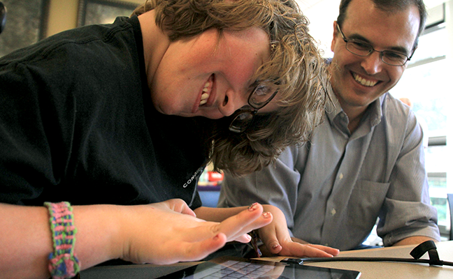 An instructor works with a student using a tablet