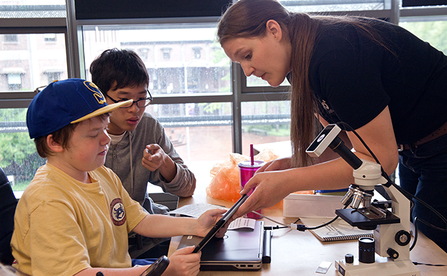 An educator shows two students how data is displayed on a tablet