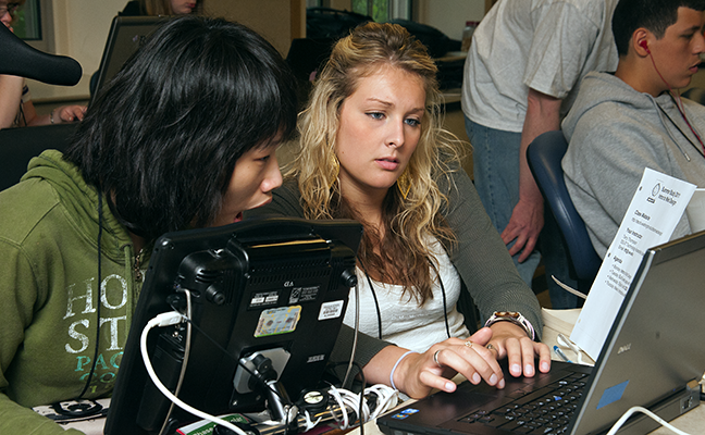 Two students use assistive technology to work on a computing project