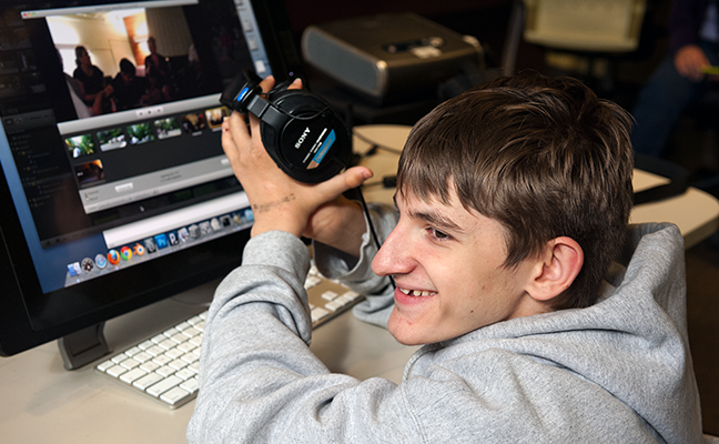A student uses headphones to work on a computing project A student uses headphones to work on a computing project