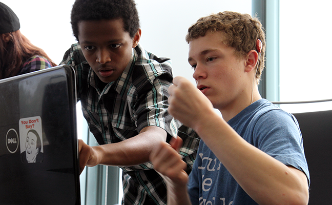 A computing student uses sign language to communicate to with another student