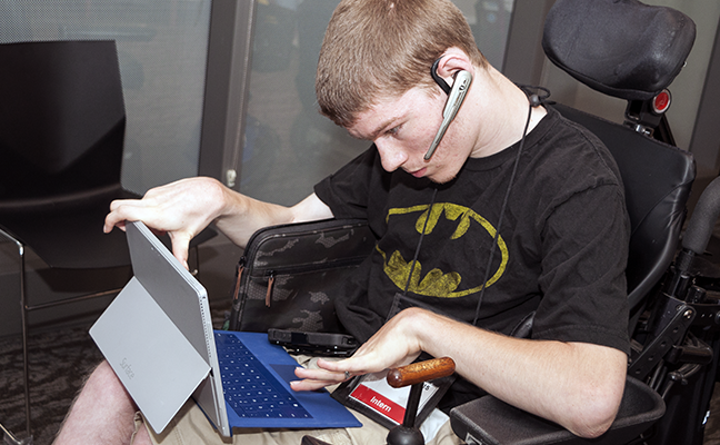 A student uses a headset, tablet, and keyboard to work on a project