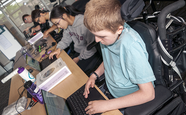 A group of students with diverse abilities work in a computer lab