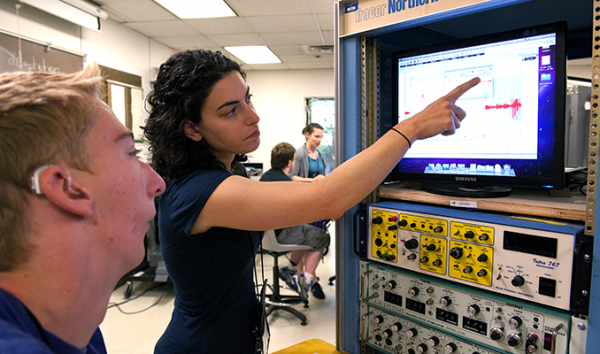 A student with a hearing impairment and an educator look at data on a monitor