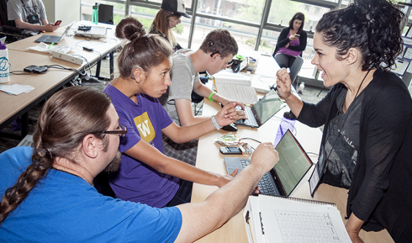 A computing student works with a sign language interpreter and a computing educator