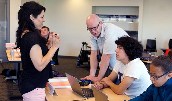 A student looks to an interpreter while the educator shows him how to design a website. A student looks to an interpreter while the educator shows him how to design a website.