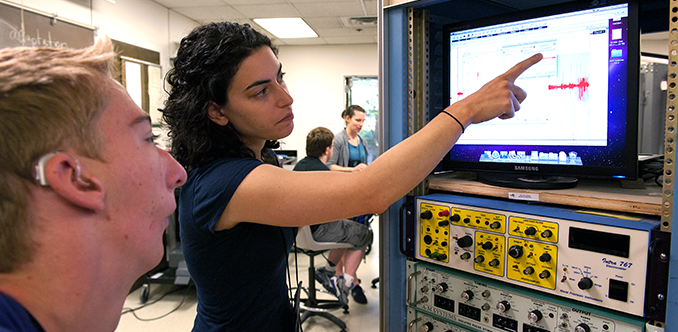 A student with a hearing impairment and an educator look at data on a monitor A student with a hearing impairment and an educator look at data on a monitor