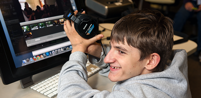 A student uses headphones to work on a computing project A student uses headphones to work on a computing project