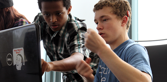 A computing student uses sign language to communicate to with another student