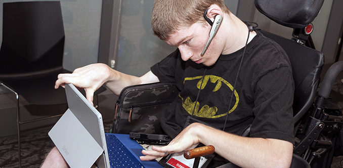 A student uses a headset, tablet, and keyboard to work on a project