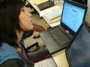 A woman uses a computer as well as assistive technology.