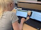 A student uses screen enlarging software and two laptops to work on a coding project.