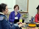 A faculty member with a disability types on a computer while students work in the background.