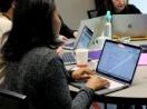 A woman works on a computer at a table with others.