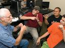 Richard signs with a group of students surrounded by computers.