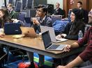 Attendees of SIGSCE laugh and smile while using computers.