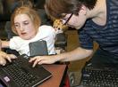 A female mentor working with a female student with a disability on a computer.