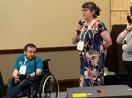 AccessComputing Director Brianna Blaser hosts two speakers with microphones towards the front of a room.