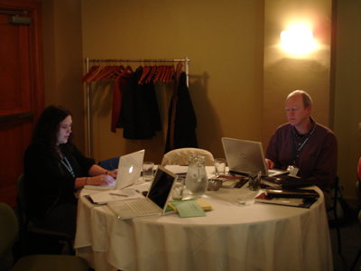 Two people working on laptops at a conference