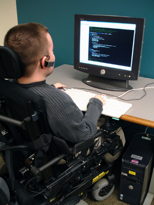 A student sitting in a wheelchair uses a computer