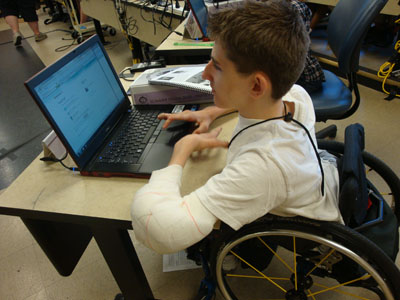 A student sitting in a wheelchair uses a computer
