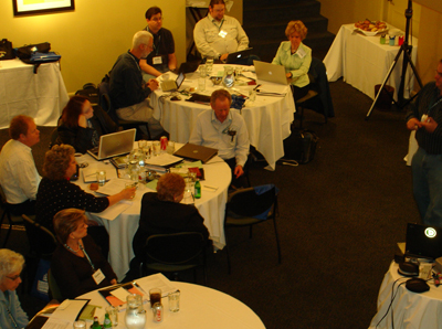 People sitting at round tables, listening to someone speak