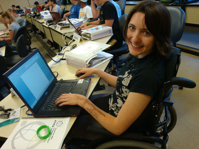 A student sitting in a wheelchair uses a laptop