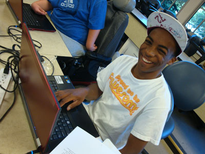 A student using a laptop smiles