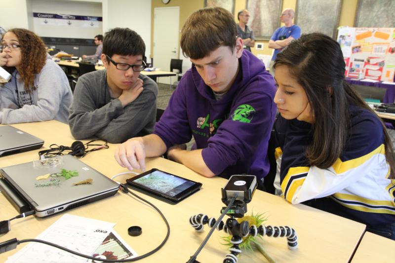 Three students utilize a tablet.